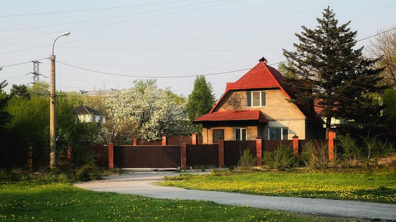 Загородный дом с красной крышей среди весенней зелени участка