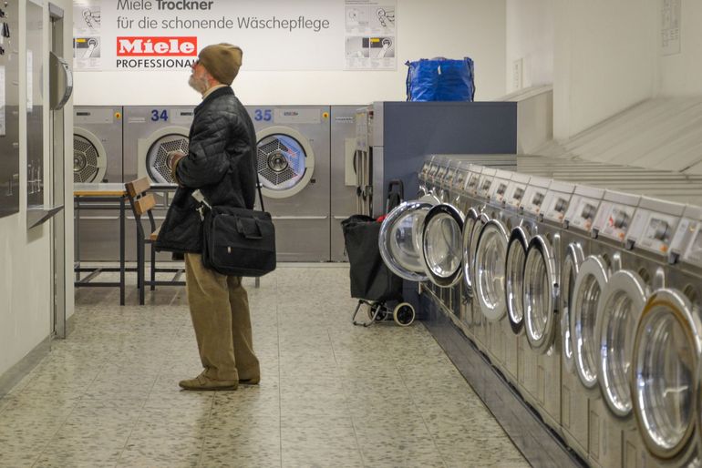 Ряд стиральных машин Miele в прачечной у стены