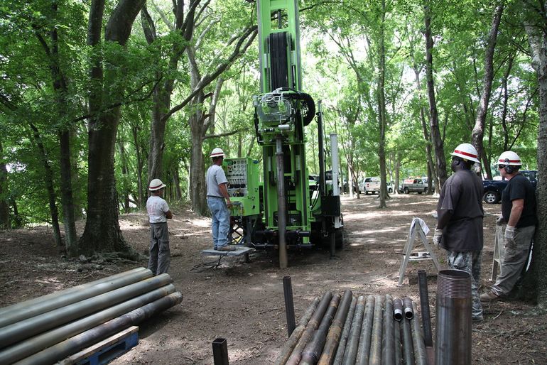 Буровая установка с трубами во время работ на грунтовой площадке